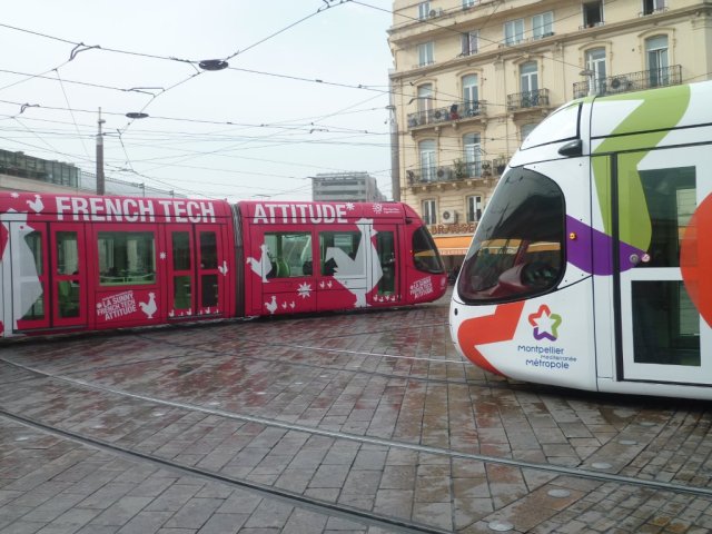 Place Auguste-Gibert à Montpellier, le vendredi 20 mars 2015, à 10h45 pile, la rame 2049 Citadis 302 Alstom multilignes à la livrée "Montpellier Méditerranée Métropole" cède le passage à la rame 2048 Citadis 302 Alstom multilignes à la livrée "La Sunny French Tech Attitude". Copyright : Edouard Paris