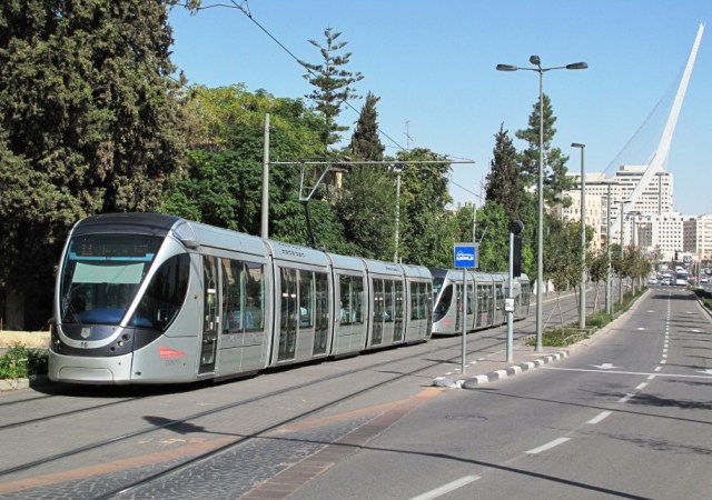 Un binôme de rames Citadis 302 Alstom, rame numéro 16 en tête, circulant en direction du terminus "Mount Herzl", est photographié sur la ligne rouge de Jérusalem à l'approche de la station "Kiryat Moshe". En arrière plan, le mât incliné de 119 mètres de haut du Pont de Cordes de l'architecte espagnol Santiago Calatrava Valls. Photo prise le lundi 2 novembre 2015. Copyright : Jaco